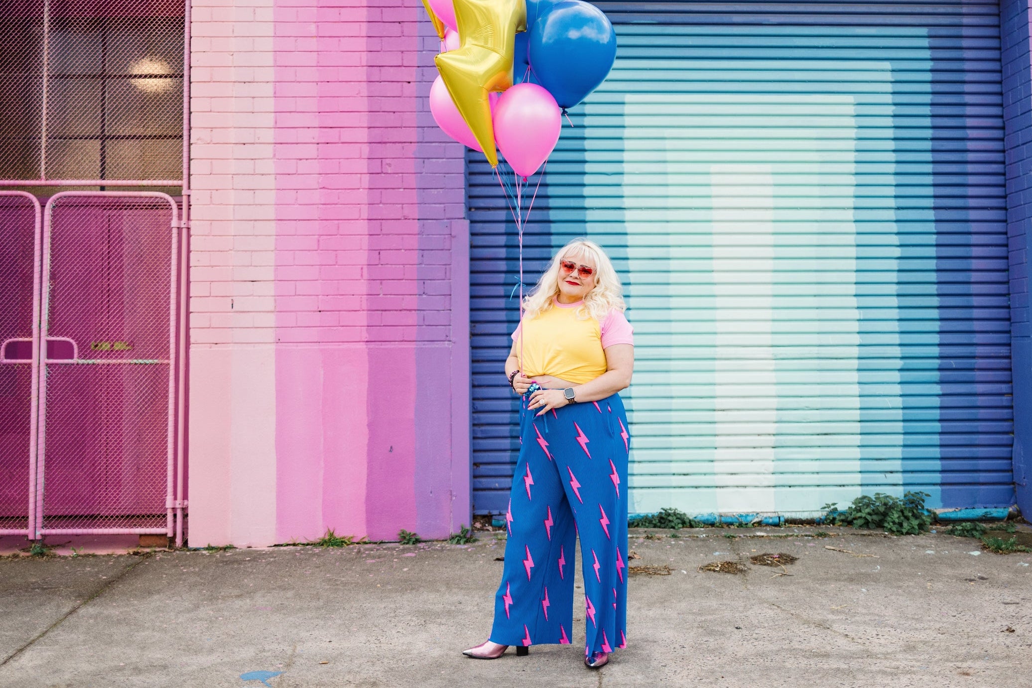 Person holding colorful balloons in front of a pink and blue building with 'Records' written on it.